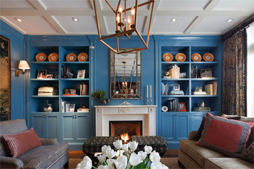 Living room with built in bookcases surrounding fireplace and beautiful custom framed mirror.