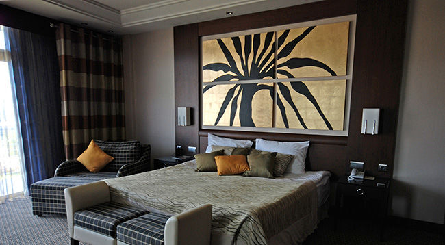 Photo of beautifully decorated hotel bedroom with four piece custom framed artwork on the wall.